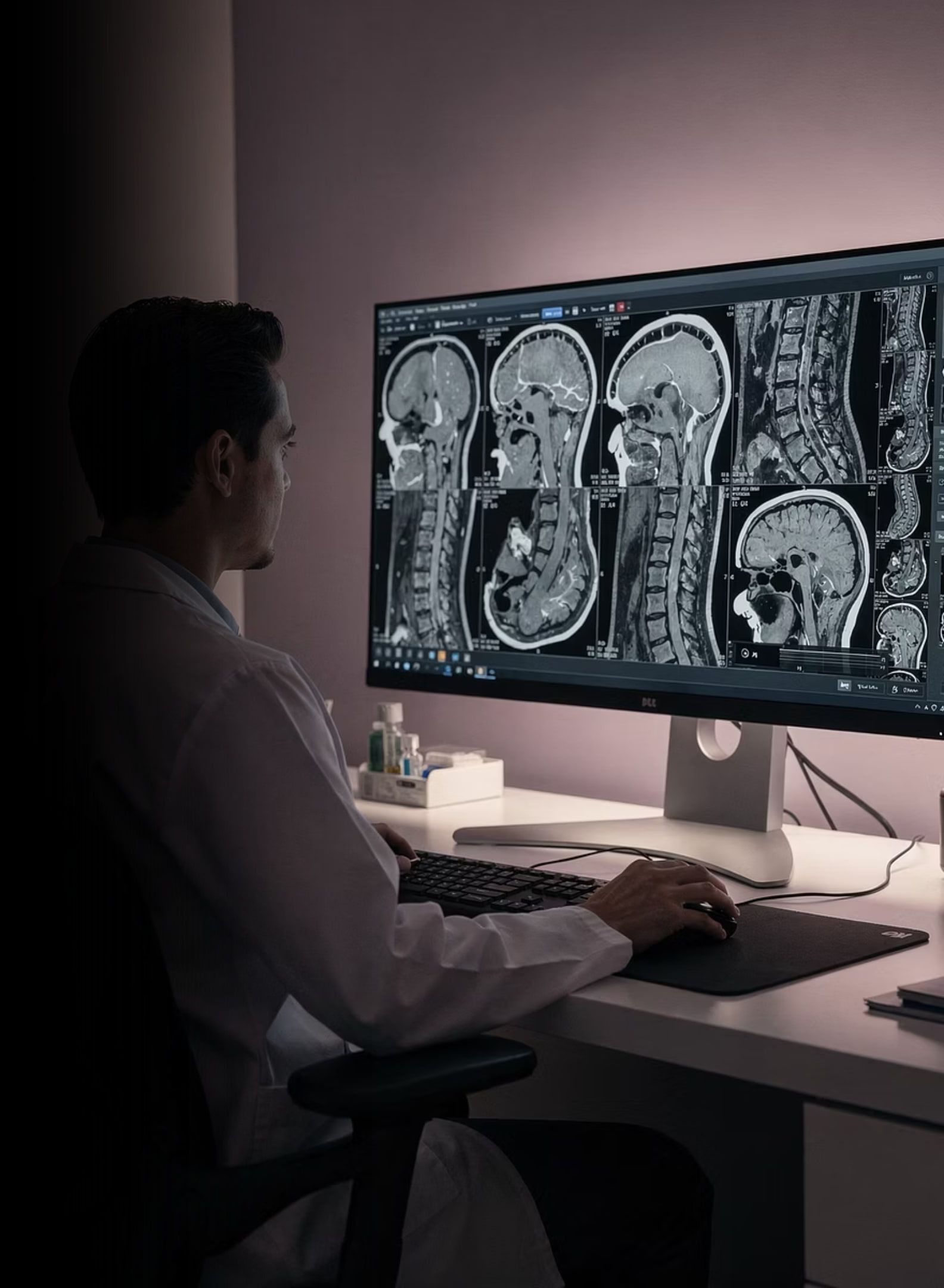 A radiologist reviewing spinal MRI sequences on a diagnostic workstation.